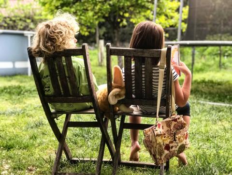 two children sat in deskchairs with backs to camera having a chat