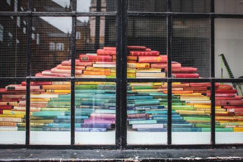 image of multicoloured books in a pyramid behind a window